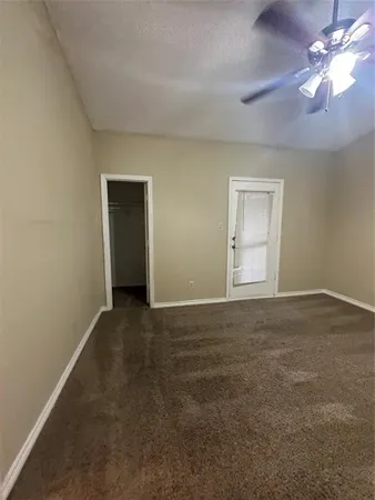 a view of an empty room with window and a ceiling fan