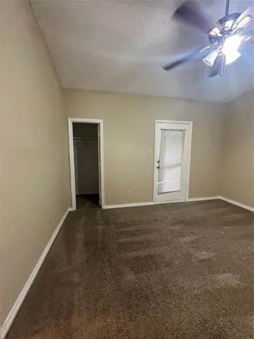 a view of an empty room with window and a ceiling fan