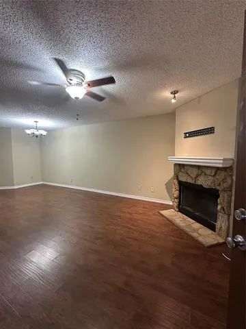 an empty room with wooden floor fireplace and fan