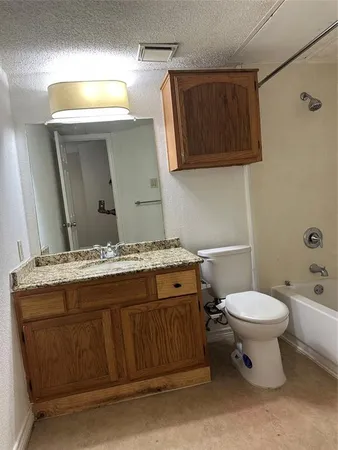 a bathroom with a granite countertop toilet sink and mirror