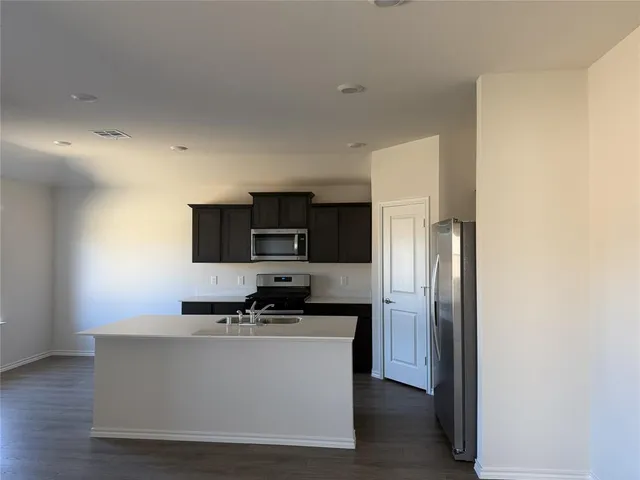 a living room with stainless steel appliances white cabinets and a refrigerator