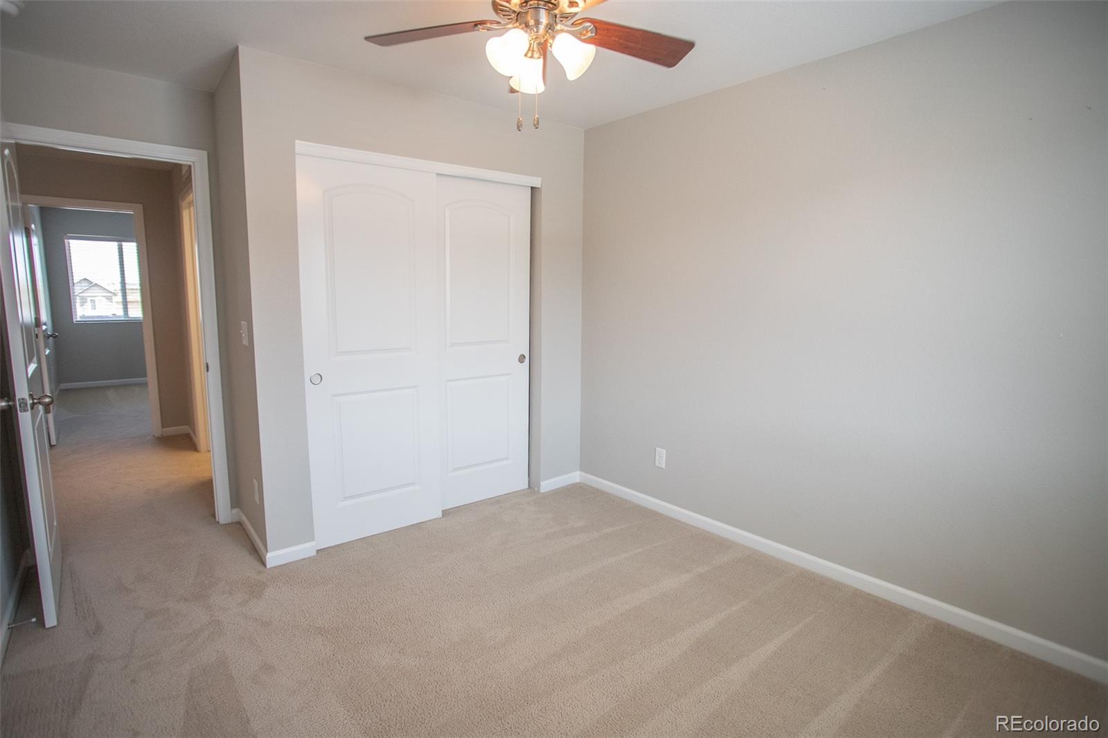 16343 East 100th Way Commerce City, CO 80022 - Photo 19 of 38 an empty room with a chandelier fan and windows