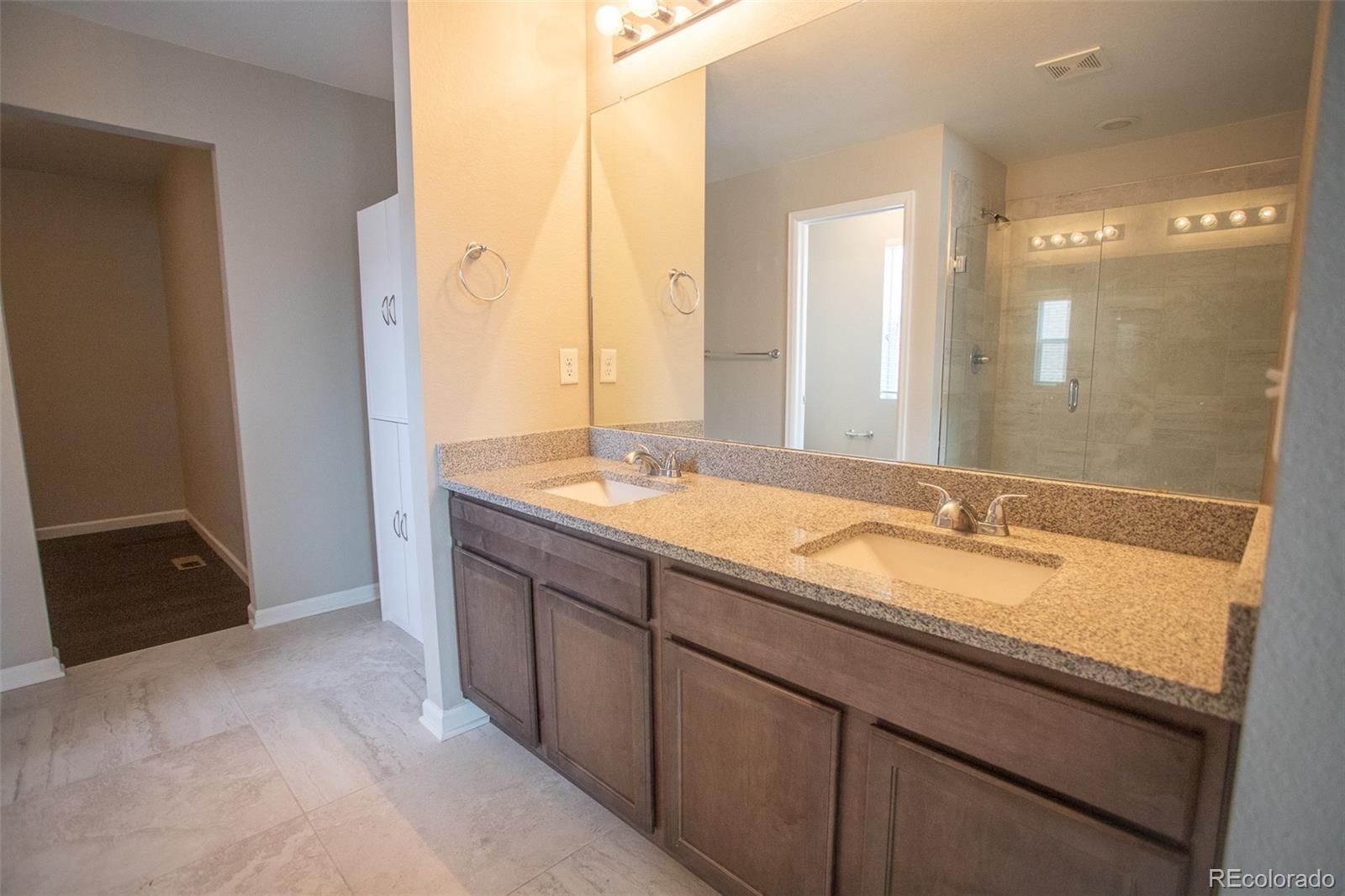 16343 East 100th Way Commerce City, CO 80022 - Photo 28 of 38 a bathroom with a granite countertop double vanity sink and mirror