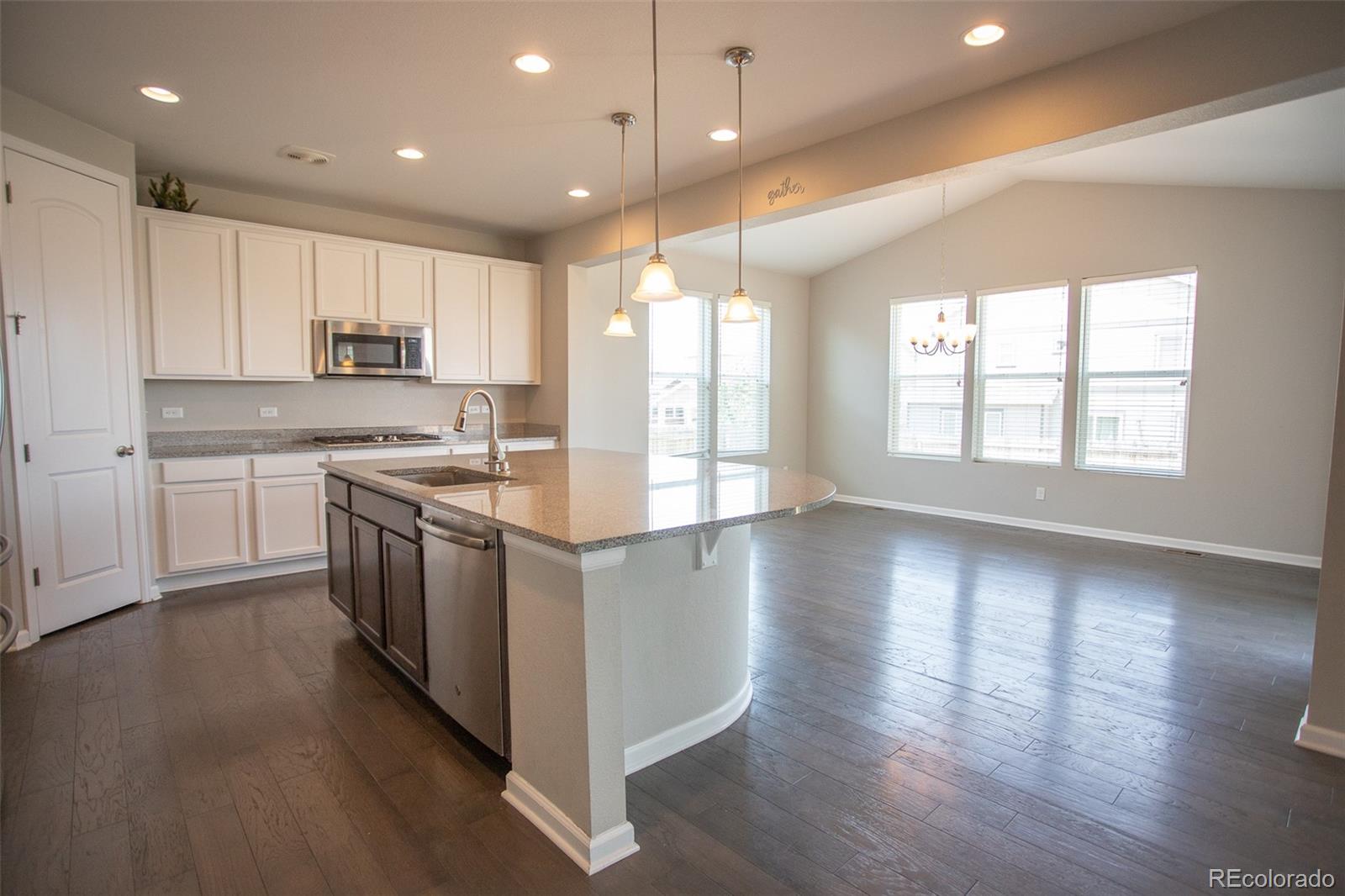 16343 East 100th Way Commerce City, CO 80022 - Photo 6 of 38 a kitchen with stainless steel appliances granite countertop a stove a sink a refrigerator and white cabinets with wooden floor