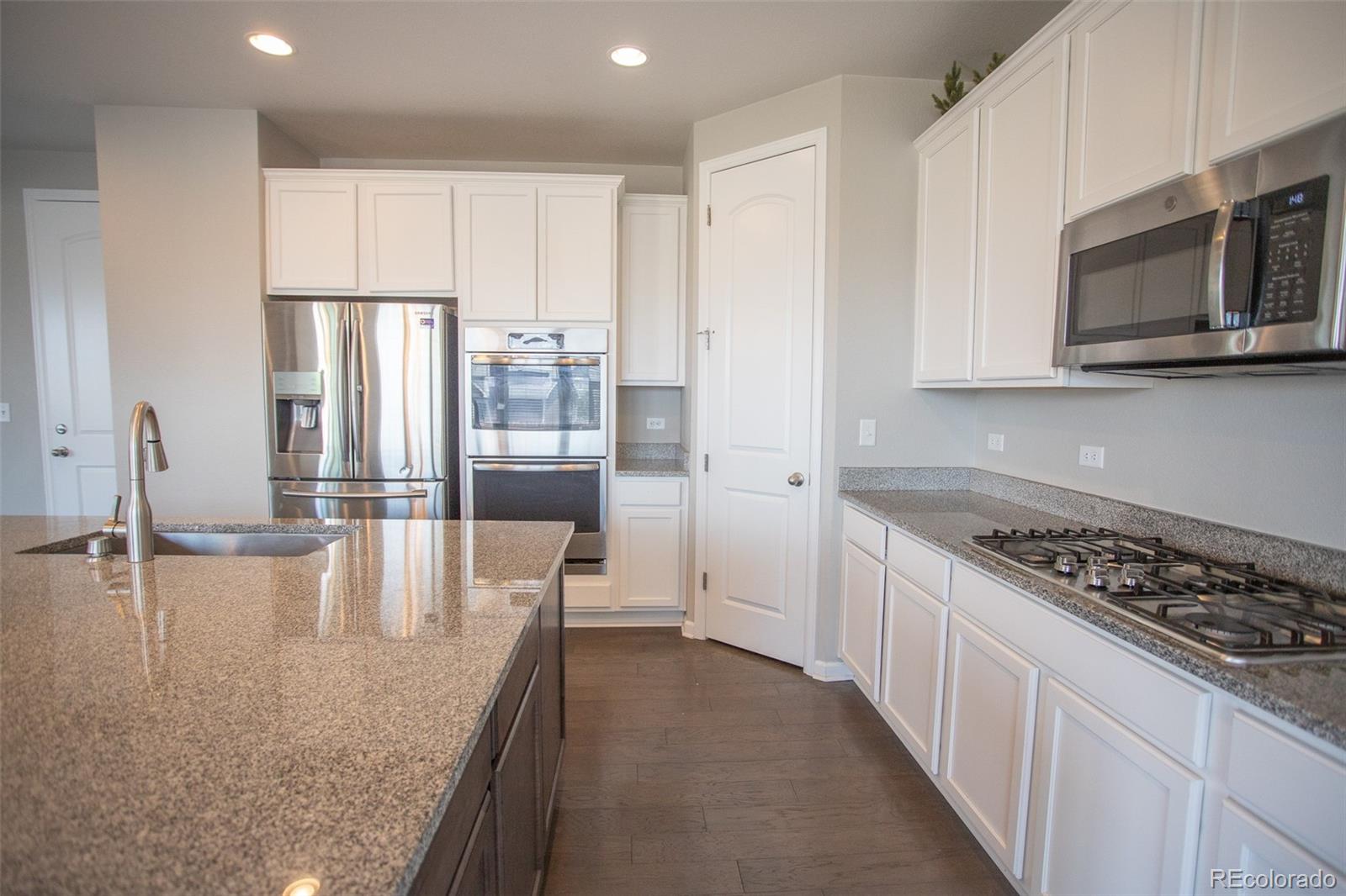 16343 East 100th Way Commerce City, CO 80022 - Photo 9 of 38 a kitchen with stainless steel appliances granite countertop a stove a sink and a microwave
