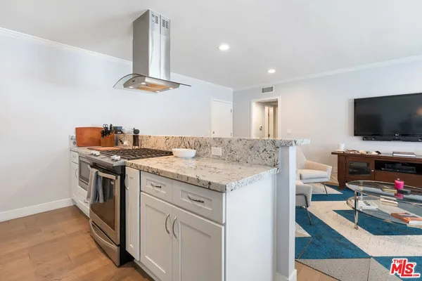 a kitchen with a stove and a flat screen tv
