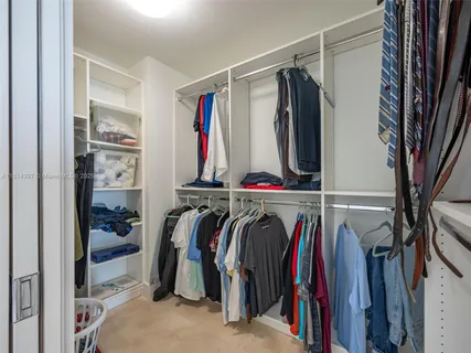 a view of walk in closet with clothes and shoes