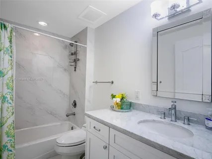 a bathroom with a granite countertop sink a toilet and shower
