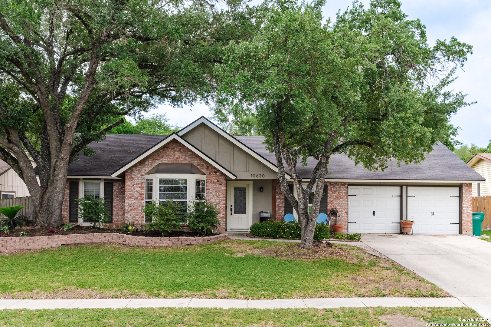 a front view of a house with a garden and trees