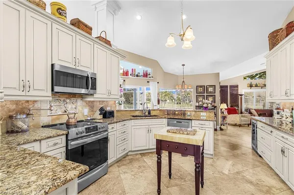 a kitchen with stainless steel appliances granite countertop a stove top oven a sink dishwasher and white cabinets with wooden floor