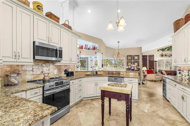 a kitchen with stainless steel appliances granite countertop a stove top oven a sink dishwasher and white cabinets with wooden floor