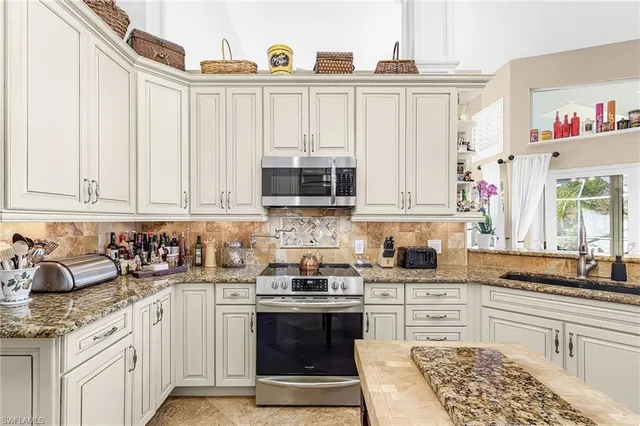 a kitchen with stainless steel appliances granite countertop a stove a sink and a microwave