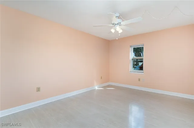 an empty room with a window and a fan