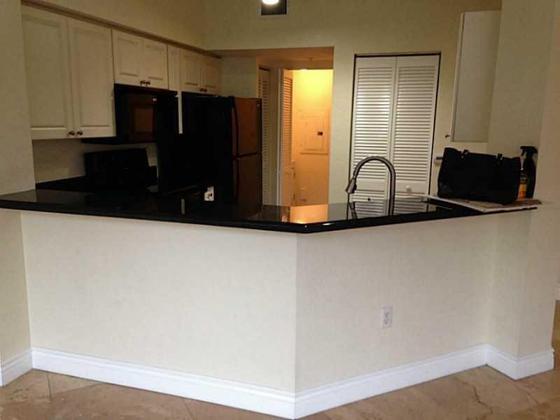 6702 West Sample Road, Unit 6702 Coral Springs, FL 33067 - Photo 3 of 8 a kitchen with a refrigerator and cabinets