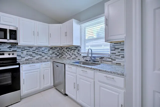 a kitchen with stainless steel appliances granite countertop white cabinets sink and dishwasher