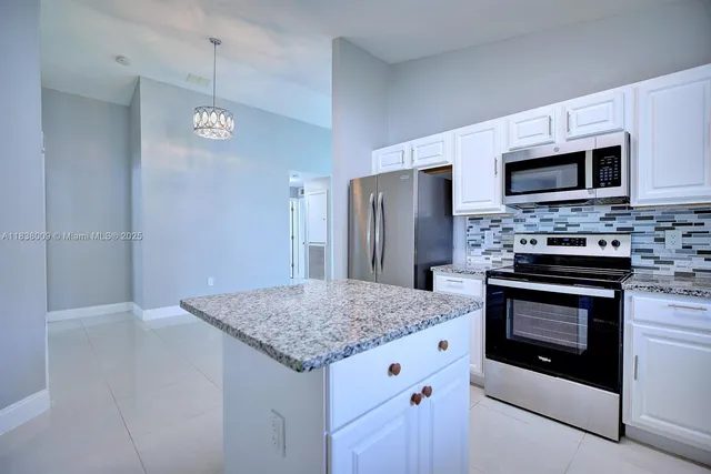 a kitchen with stainless steel appliances granite countertop a refrigerator and a stove top oven