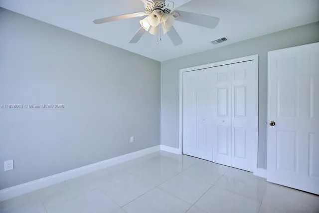a view of an empty room and chandelier fan