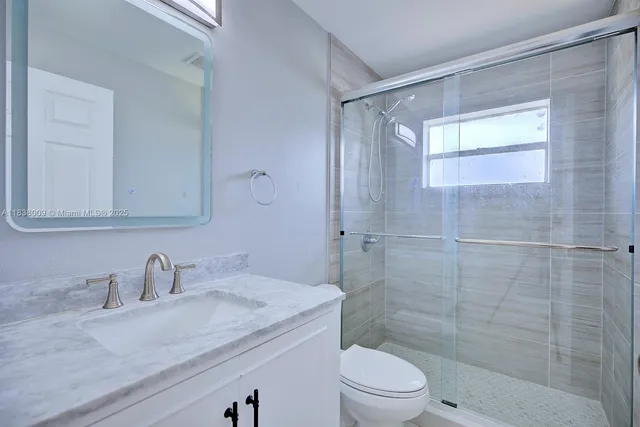 a bathroom with a granite countertop sink a toilet and shower