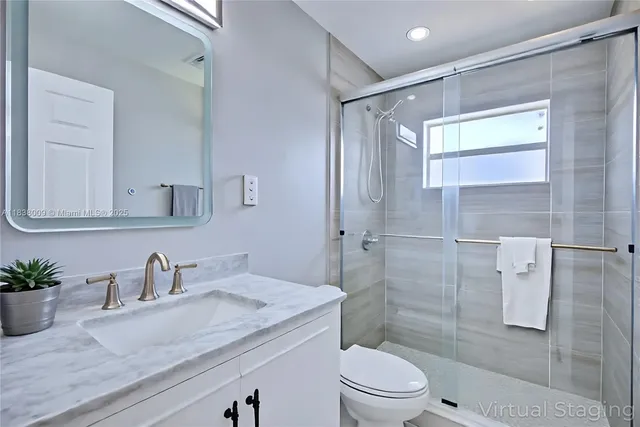 a bathroom with a granite countertop sink a toilet and shower