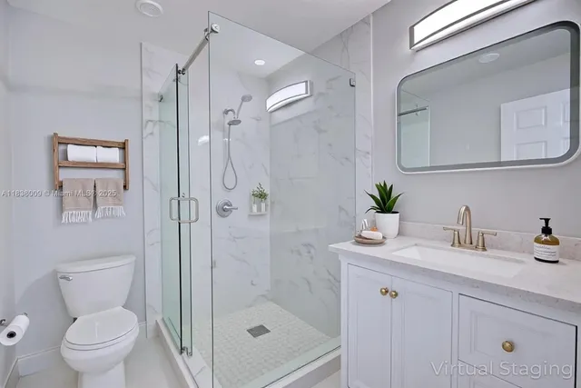 a bathroom with a shower sink vanity mirror and toilet