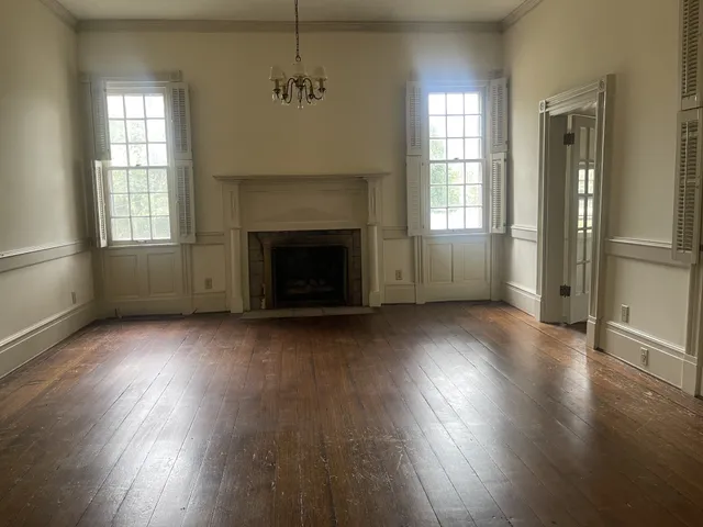 an empty room with wooden floor a fireplace and windows