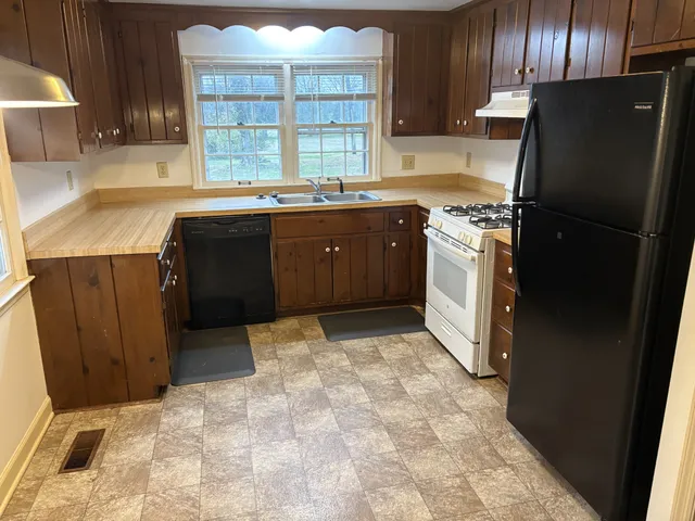 a kitchen with a sink a refrigerator and wooden cabinets