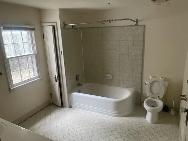 a bathroom with a white toilet and bathtub