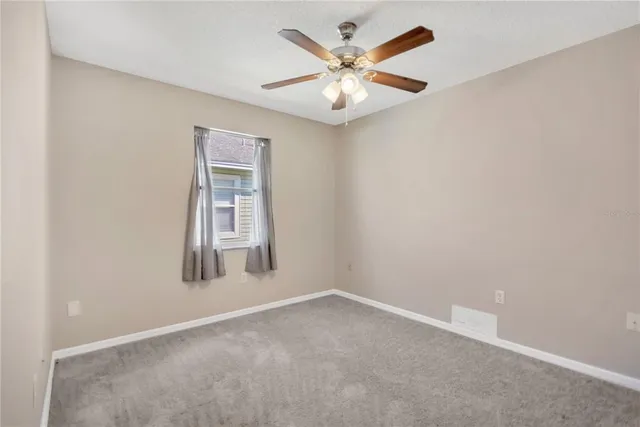 an empty room with a chandelier fan and closet area