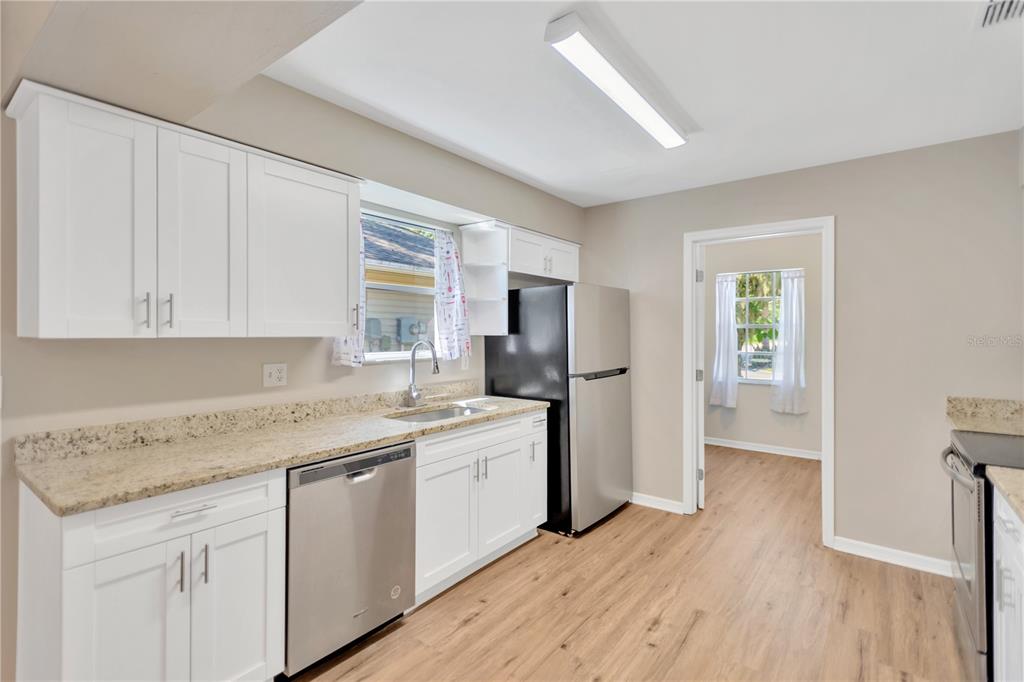3600 Raintree Terrace Lakeland, FL 33803 - Photo 6 of 22 a kitchen with a sink dishwasher a stove and white cabinets with wooden floor
