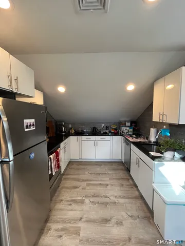 a large kitchen with stainless steel appliances a large counter top a stove and a refrigerator