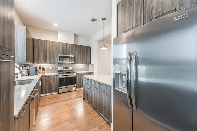 a kitchen with kitchen island a large counter top space a sink stainless steel appliances and cabinets