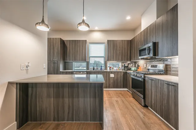 a large kitchen with granite countertop a stove top oven a sink dishwasher and wooden cabinets with wooden floor