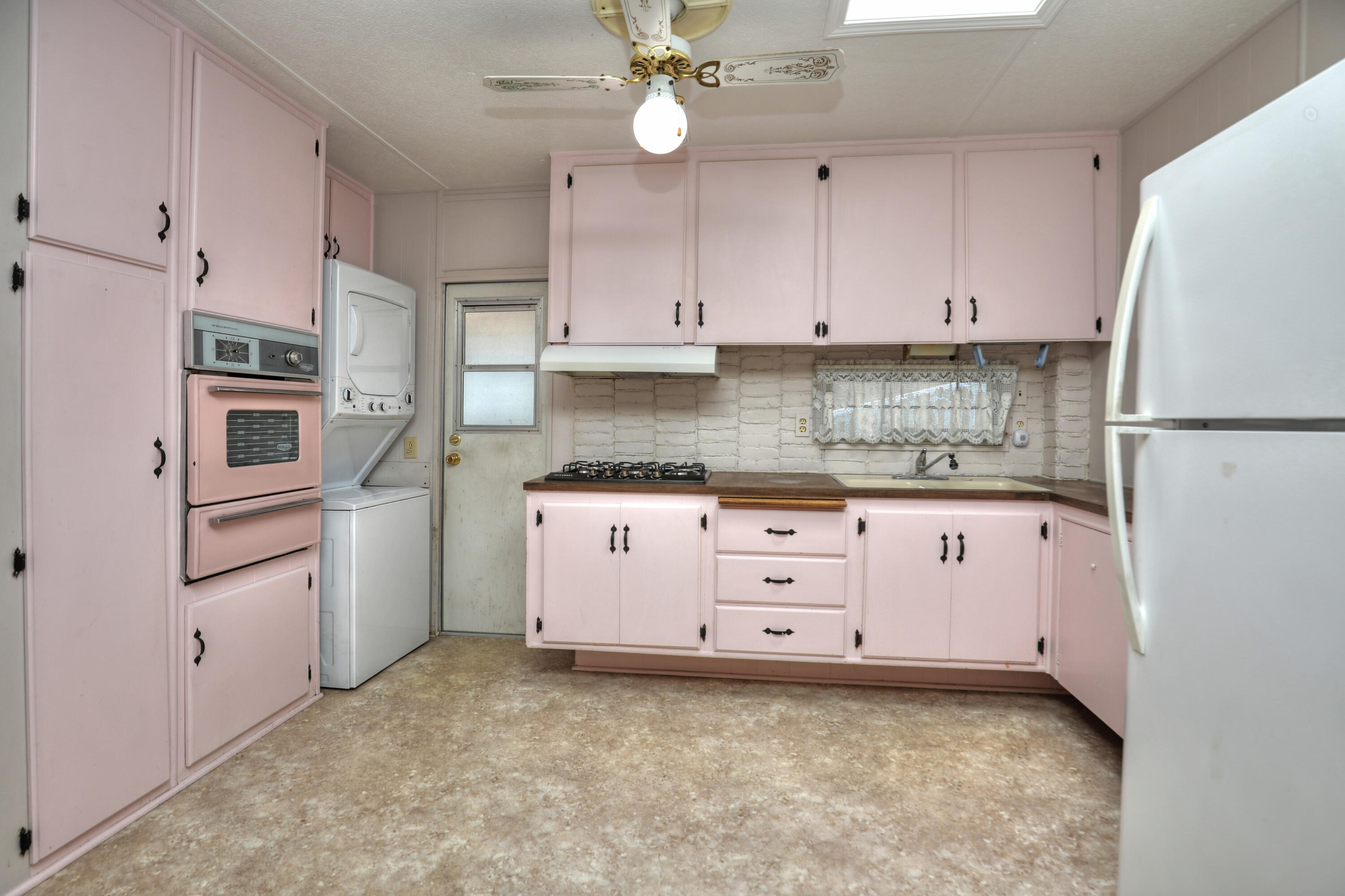 333 Old Mill Road, Unit 102 Santa Barbara, CA 93110 - Photo 7 of 16 a kitchen with granite countertop a white refrigerator oven a sink with cabinets and wooden floors