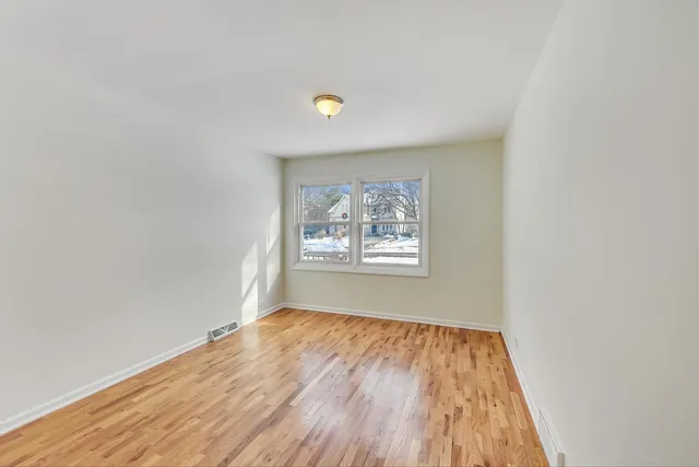 a view of a big room with wooden floor and windows