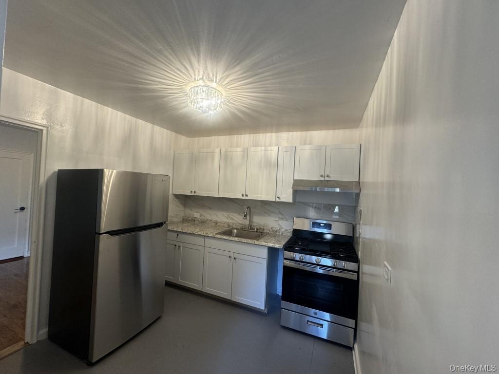 5639 Netherland Avenue, Unit 1B Bronx, NY 10471 - Photo 4 of 8 Kitchen with stainless steel appliances, light stone countertops, finished concrete flooring, under cabinet range hood, and tasteful backsplash