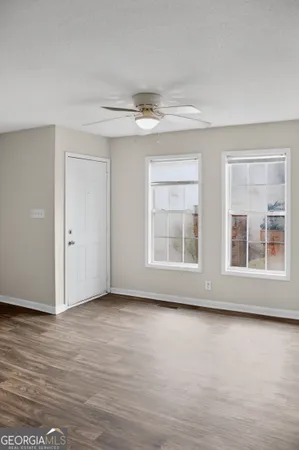 a view of an empty room with a window and wooden floor