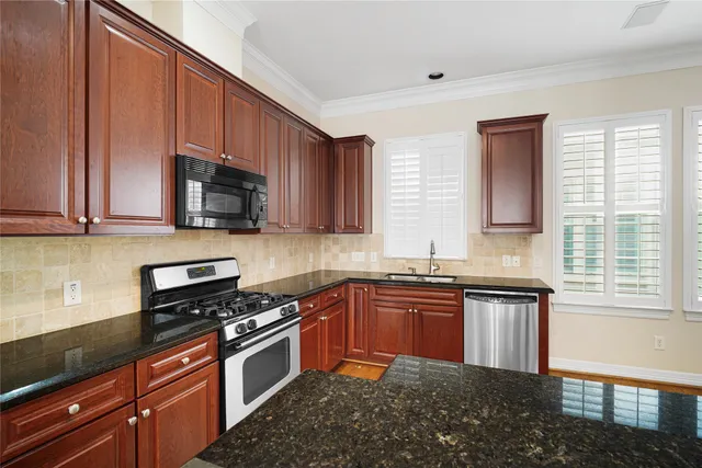 a kitchen with stainless steel appliances a sink a stove a microwave cabinets and a counter top space