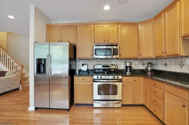 a kitchen with stainless steel appliances granite countertop a refrigerator a stove top oven a sink and dishwasher