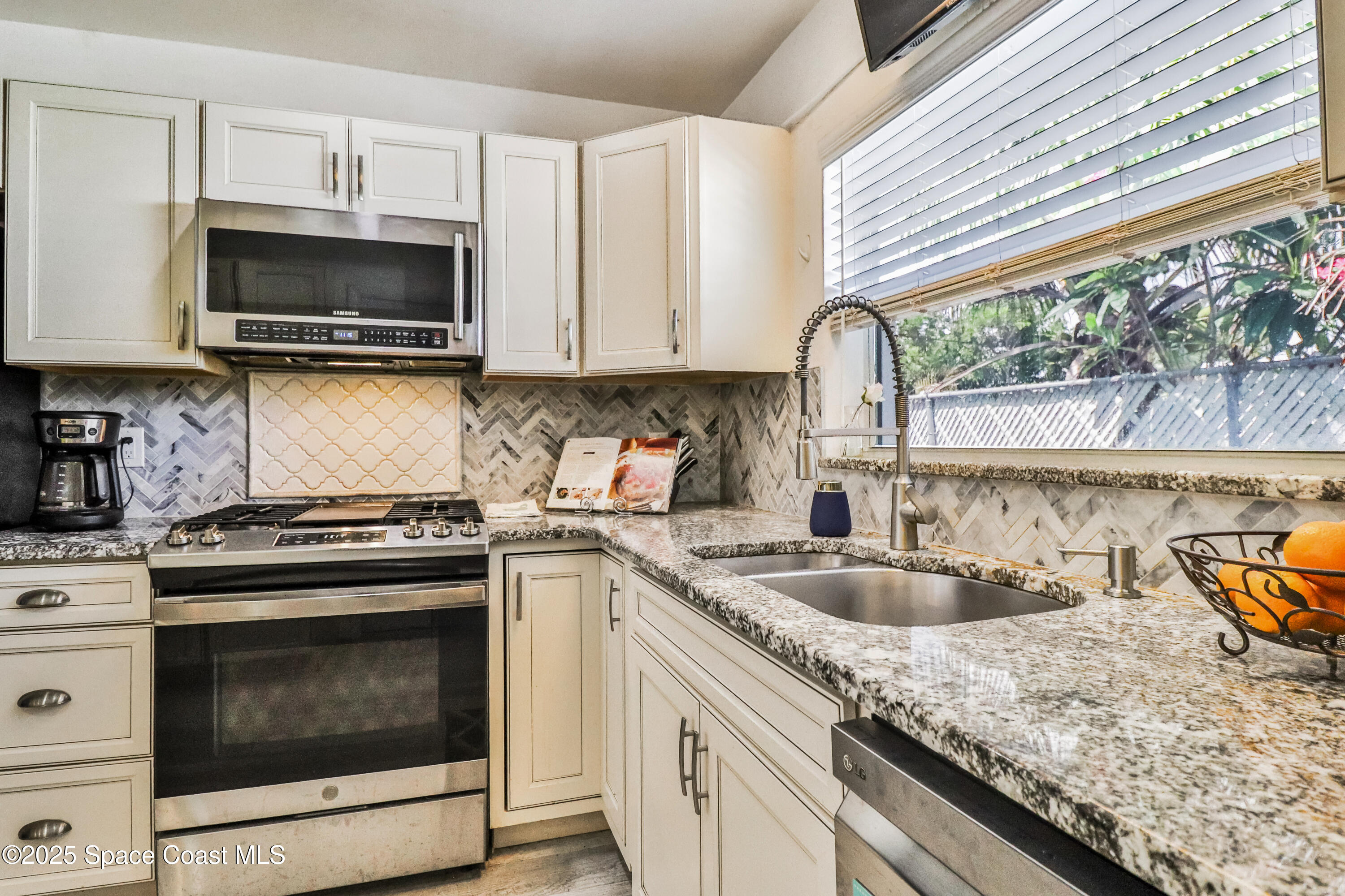348 Berkeley Street Satellite Beach, FL 32937 - Photo 13 of 46 a kitchen with granite countertop a sink a stove and a microwave