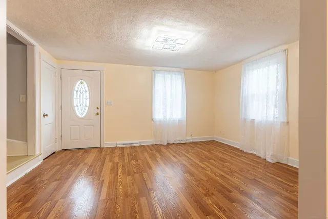 a view of an empty room with window and wooden floor