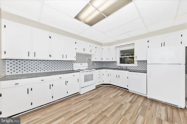 a kitchen with granite countertop white cabinets and white appliances
