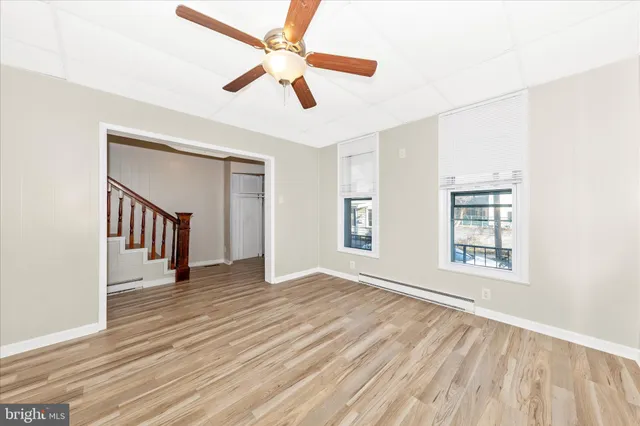 a view of empty room with wooden floor and fan