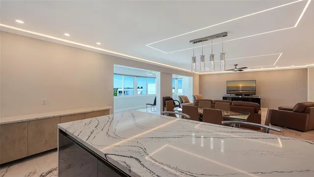 a kitchen with stainless steel appliances granite countertop a sink a stove a microwave a refrigerator cabinets and chairs