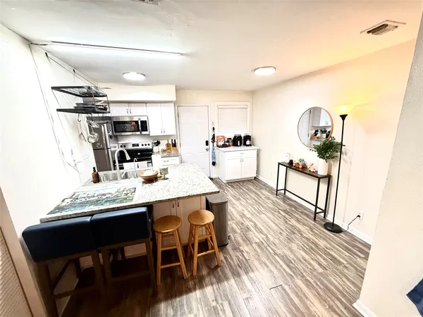 a dining hall with stainless steel appliances kitchen island a table and chairs in it