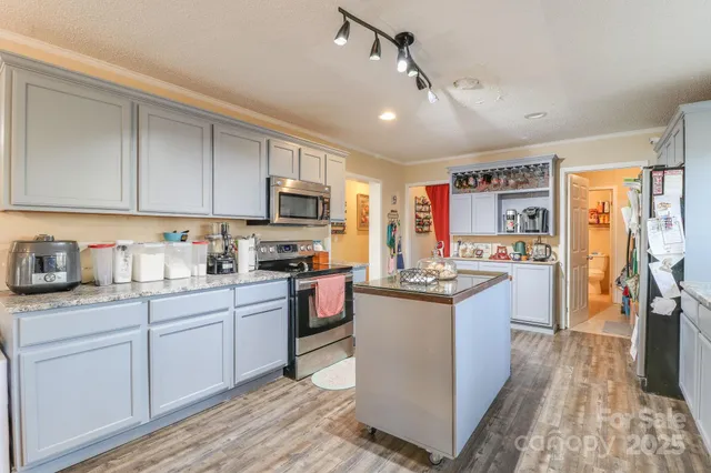 a kitchen with stainless steel appliances granite countertop a stove top oven a sink dishwasher a refrigerator and cabinets with wooden floor