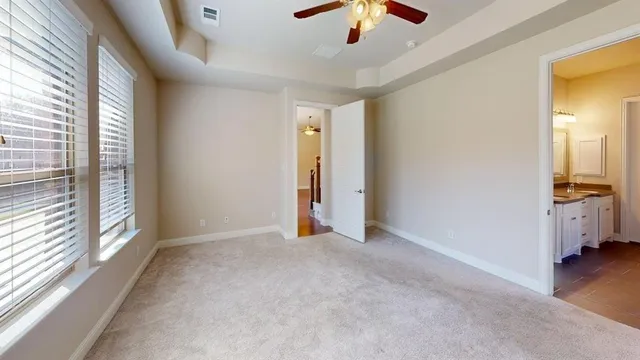 an empty room with chandelier fan and windows