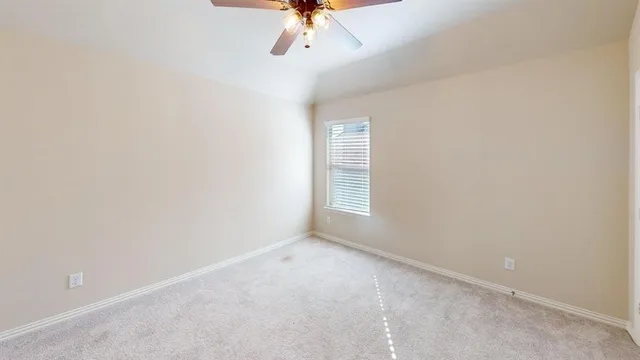 an empty room with a chandelier fan and windows