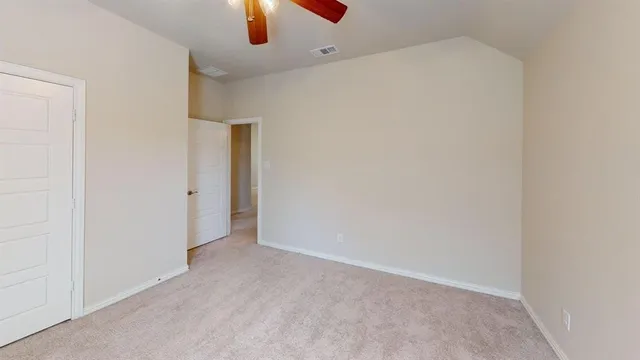an empty room with ceiling fan and window
