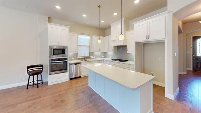 a kitchen with white cabinets and stainless steel appliances