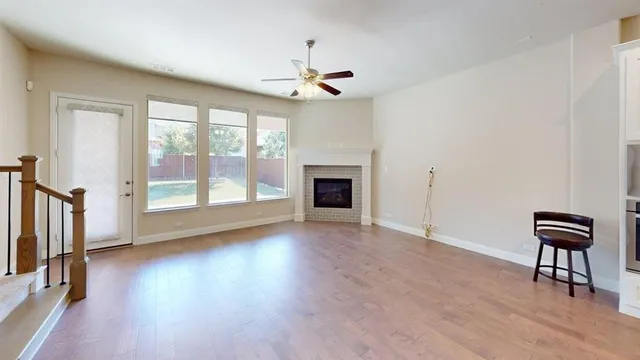 an empty room with wooden floor fan and windows